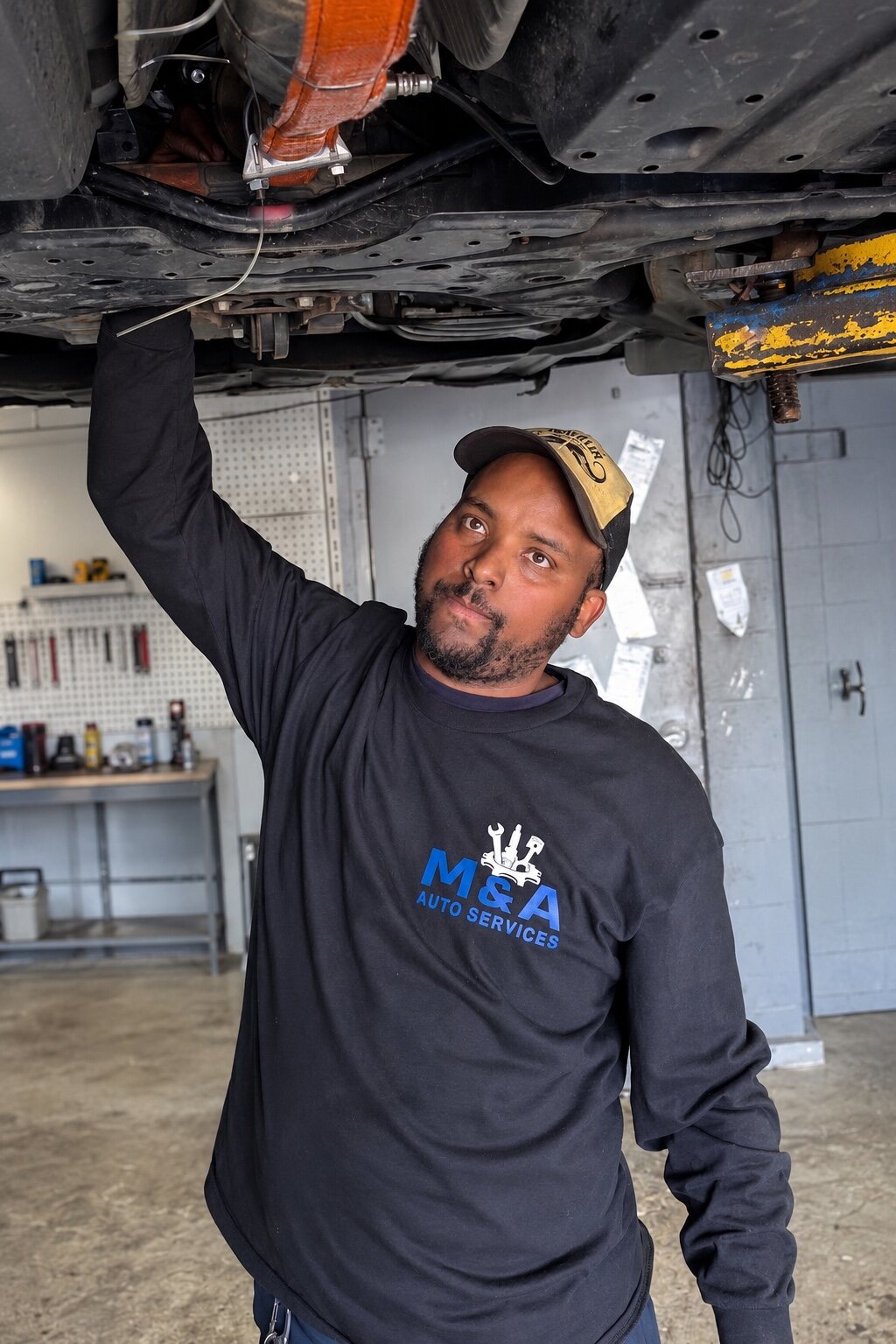 M&A technician inspecting the underside of a vehicle